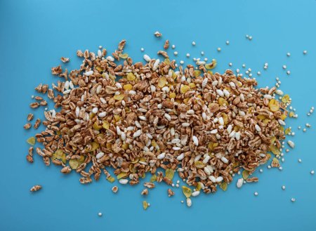 Mischung aus gepufftem Müsli auf hellblauem Hintergrund. Haferflocken, Quinoa, Reis und Cornflakes