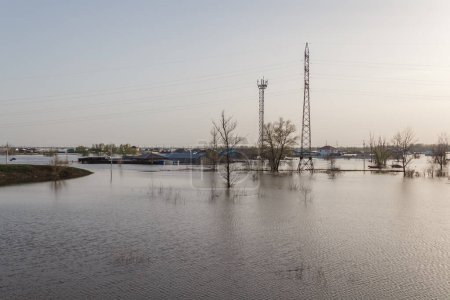 Überschwemmung in Kasachstan. Ein Dorf, das von Wasser überflutet wurde. Der Fluss trat über die Ufer. Schmelzwasser auf dem Feld. Unterstützung der Stromleitungen bei Hochwasser.