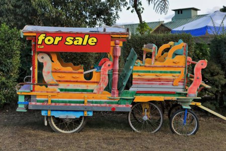 Téléchargez les photos : Chariot pour enfants multicolore pour emmener les enfants faire un tour, à vendre et exposé dans un terrain à côté de la route Gillies Range pour que les passants puissent le voir. Yungaburra-Atherton Tablelands-QLD-Australie. - en image libre de droit