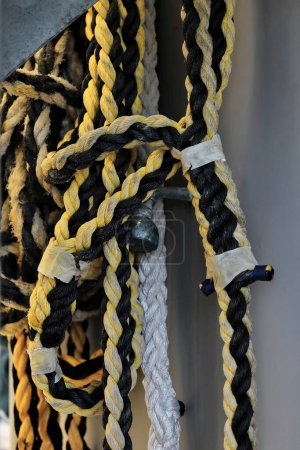 Photo for Cable laid-multi strand-synthetic-black and yellow-white rope coil hanging on the deck of a tourist pontoon for swimming-snorkeling-scuba diving moored on the Great Barrier Reef. Cairns-QLD-Australia. - Royalty Free Image