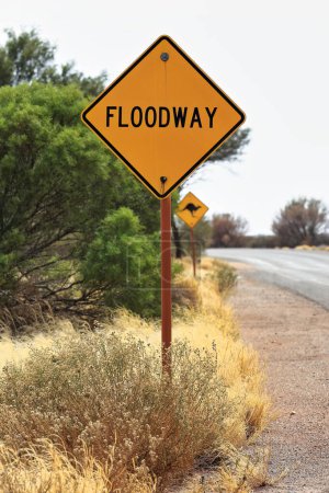 Photo for W-5-7-1 road sign: black FLOODWAY word on diamond-shaped yellow background reminds drivers that they about to cross a floodplain-shallow depression that is subject to flooding. Petermann-NT-Australia. - Royalty Free Image