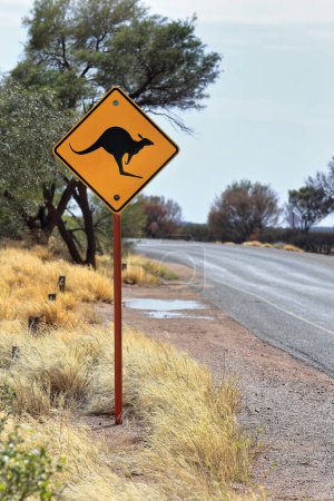 Photo for W5-29-1 road sign: black kangaroo picto on diamond-shaped yellow background warns drivers to pay attention to potentially hazardous animals that can be roaming on the roads. Petermann-NT-Australia. - Royalty Free Image