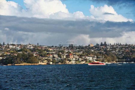 Foto de Vivienda frente al mar en el puerto del suburbio de Vaucluse con la bahía de Perejil a la derecha con su pasarela colgante y el faro Macquarie a la izquierda en la cima de la ladera. Sydney Harbour-NSW-Australia - Imagen libre de derechos