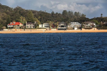 Photo for Camp Cove Beach on South Head peninsula harborside-lapped by turquoise water-backed by luxury seafront mansions as seen from the Manly-Circular Quay ferry. Watsons Bay-Sydney Harbour-NSW-Australia. - Royalty Free Image
