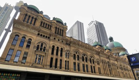 Photo for The Heritage-listed Queen Victoria Building finished in 1898 in Romanesque Revival style, facade facing George Street with background of modern tall skyscrapers and towers. Sydney CBD-NSW-Australia. - Royalty Free Image