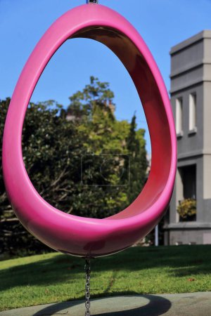 Photo for Pink-red egg swing with steel upright pole and chain, allegory of motherhood and fertility on the former Royal Hospital for Women site, now the homonymous park. Paddington suburb-Sydney-NSW-Australia. - Royalty Free Image