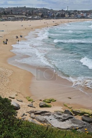 Photo for Southwest-northeast view of almost the total length of Bondi Beach backed by the beachfront buildings on Campbell Parade as seen from Notts Avenue. Sydney-NSW-Australia. INCIDENTAL PEOPLE IN THE IMAGE - Royalty Free Image