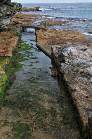 Foto de Canal de corte de roca que comunica la piscina de marea de Wally Weekes y la piscina infantil con el mar abierto en el extremo noreste de North Bondi Beach en la marea ascendente. Sydney-Nueva Gales del Sur-Australia. - Imagen libre de derechos