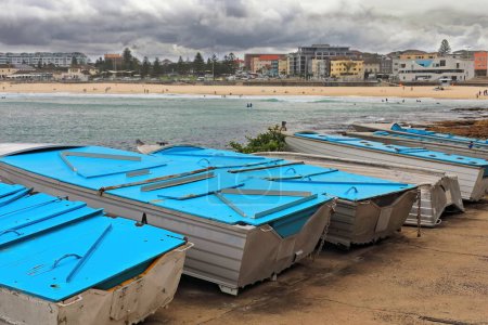 Photo for Fishing boats ashore on the Ben Buckler Point area facing North Bondi Beach backgrounded by The Playground, the beachfront buildings at Campbell Parade and the Life Saving Club. Sydney-NSW-Australia. - Royalty Free Image