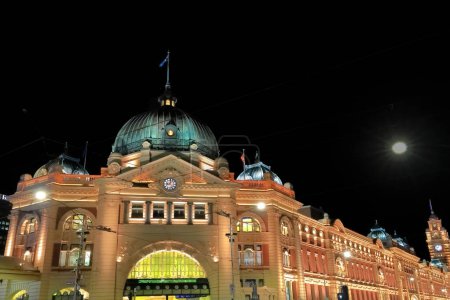 Foto de Edificio de la estación de tren de Flinders Street desde el año 1909 en estilo eduardiano bajo la luna llena en la esquina de Flinders y Swanston Streets con sus relojes cúpula-arco de entrada-torre. Melbourne-VIC-Australia - Imagen libre de derechos