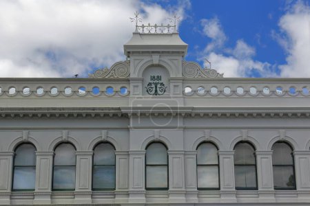 Photo for Renaissance revival building from 1881 featuring a round arched sash windows run, balustrade parapet and central gablet with lateral scroll decorations on clear-colored facade. Ballarat-VIC-Australia. - Royalty Free Image