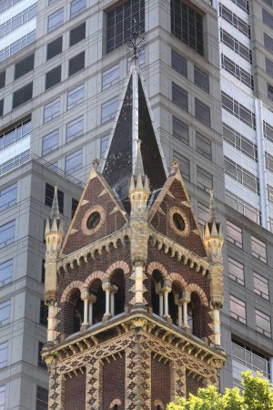 Téléchargez les photos : Haut clocher carré de l'AD 1866 construit dans le style néoroman lombard église Saint-Michel Uniting soutenu par les grands gratte-ciel du CBD sur Collins Street N côté. Melbourne-VIC-Australie - en image libre de droit