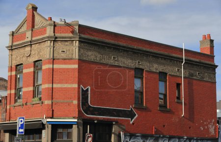 Foto de Edificio comercial en el estilo de la Federación 1900 de ladrillo rojo, esquina desplegada, ventanas verticales con banda de renderizado a nivel de la cabeza, frontón empinado, parapeto plano, en Brunswick St. Melbourne-VIC-Australia. - Imagen libre de derechos
