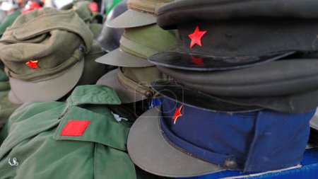 Téléchargez les photos : Ancien uniforme vert des forces militaires volontaires albanaises et divers chapeaux de campagne et casquettes de pointe de c.1981 dans les rangs aboli, période communiste pro-chinoise, Pazari i Ri-New Bazaar. Tirana-Albanie - en image libre de droit