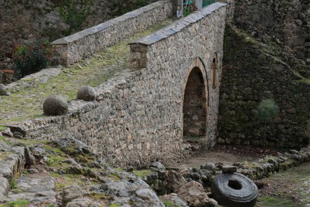 Foto de Puente de mampostería de piedra en el camino empedrado que conduce al Dollma Tekke-Teqja e Dollmes o Hajji Mustafa Baba Tekke, pequeño santuario islámico sufí construido en 1780 dentro del recinto del castillo. Kruja-Albania. - Imagen libre de derechos