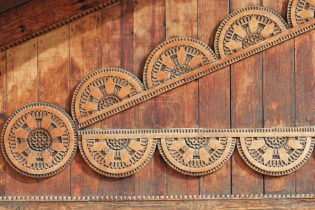 Photo for Artistic wood carvings on the wooden gable of a traditional style house, Old Bazaar-Pazari i Vjeter, displaying sunstar-shaped round motifs, ranging from full circles to split in two. Kruja-Albania. - Royalty Free Image