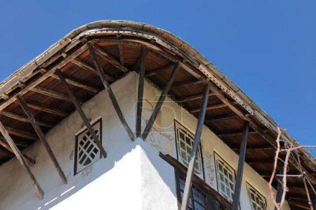 Téléchargez les photos : Grenier bondé de fenêtres projeté sur le toit à pignon pédimenté d'une maison de style ottoman de la fin du XVIIIe siècle reconstruite en 1902 dans la partie haute de la vieille ville, quartier de Palorto. Gjirokaster-Albanie - en image libre de droit