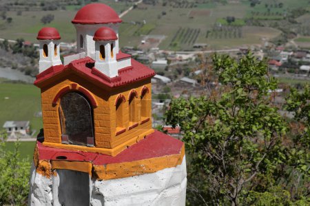 Photo for Miniature shrine of painted cement in the shape of a Byzantine-style Orthodox church, viewpoint on the dirt road climbing up from the town to Leusa village and the Saint Mary's Church. Permet-Albania. - Royalty Free Image