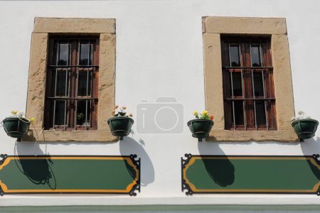 Foto de Detalle de ventanas de madera enrejada en la pared blanca de un edificio de estilo otomano de dos plantas reformado en 2016, en la zona de la Plaza Central-Sheshi Iliria, antiguo bazar Pazari i Vjeter-. Korce-Albania. - Imagen libre de derechos