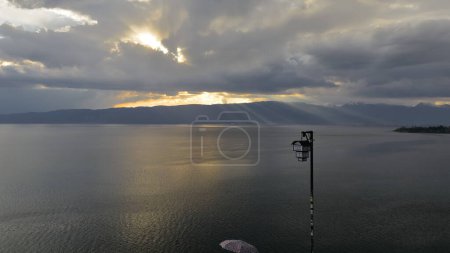 Téléchargez les photos : Rayons lumineux crépusculaires - appelés rayons de Dieu- projetant sur le bord du lac Ohrid Shebenik-Jabllanica, frontière AL-NMK, vus de l'église Saint John Kaneo en fin d'après-midi pluvieux. Ohrid-Macédoine du Nord. - en image libre de droit