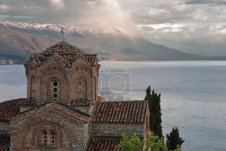Vista hacia el oeste desde el sitio arqueológico de Plaosnik sobre el San Juan Teólogo en Kaneo-Sveti Jovan Kaneo-iglesia al lago y las montañas Shebenik en el fondo. Ohrid-Macedonia del Norte.