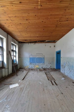 Foto de Antiguo salón de clases dentro de los restos de un edificio de la antigua escuela primaria en ruinas y abandonado de 1948 lleno de escombros con vidrios rotos y paredes y techos pelados. Vevcani-Macedonia del Norte. - Imagen libre de derechos