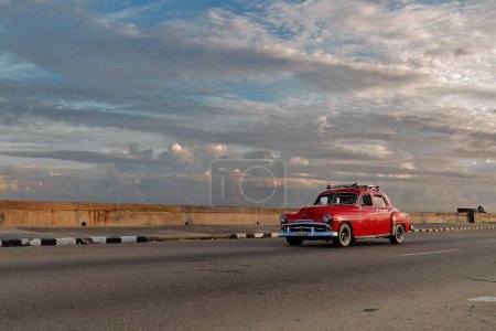 Foto de La Habana, Cuba-07 de octubre de 2019: Old red painted American classic car-almendron, yank tank- Plymouth Cranbrook 4 door Sedan from 1952 drives along El Malecn promenade in El Vedado neighborhood. - Imagen libre de derechos