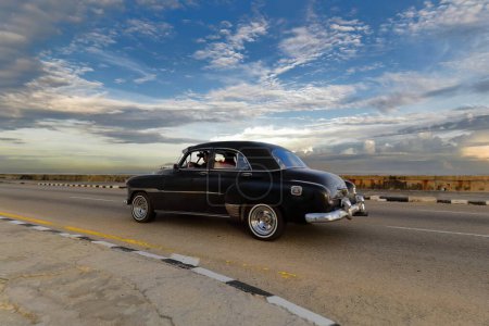Foto de La Habana, Cuba-07 de octubre de 2019: Old black painted American classic car-almendron, yank tank- Chevrolet Deluxe 4 door Sedan from 1951 drives along El Malecon promenade in El Vedado neighborhood. - Imagen libre de derechos