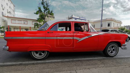 Foto de La Habana, Cuba-07 de octubre de 2019: Old red American classic car-almendron, yank tank- 1956 Ford Fairlane Town Sedan se detuvo en un semáforo rojo en la calle Linea y la esquina Avenida Presidentes, El Vedado. - Imagen libre de derechos