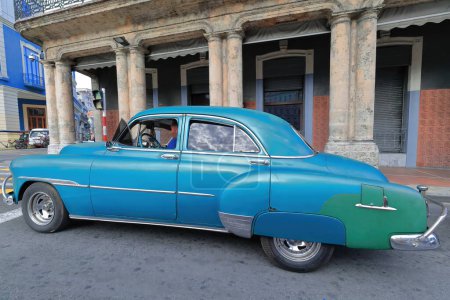 Foto de La Habana, Cuba-07 de octubre de 2019: Azul y verde viejo coche clásico americano-almendro, yanqui cisterna Chevrolet Deluxe 4 puertas Sedán de 1951 se detiene en un semáforo rojo, Paseo del Prado y Neptuno esquina de la calle. - Imagen libre de derechos