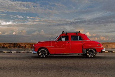 Foto de La Habana, Cuba-07 de octubre de 2019: Old red painted American classic car-almendron, yank tank- Plymouth Cranbrook 4 door Sedan from 1952 drives along El Malecon promenade in El Vedado neighborhood. - Imagen libre de derechos
