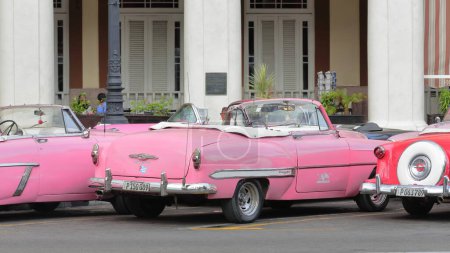 Foto de La Habana, Cuba-07 de octubre de 2019: Tres coches convertibles americanos clásicos de color rosa-rojo almendro, tanque de yanqui Mercury Monterey 1953-Chevrolet Bel Air 1953-Ford Crestline Victoria 1953 parque en el Paseo del Prado - Imagen libre de derechos
