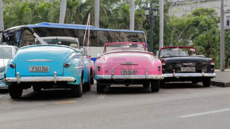 Foto de La Habana, Cuba-07 de octubre de 2019: Tres coches descapotables americanos clásicos azul-rosa-negro Ford Super DeLuxe 1947-48, Chevrolet Styleline DeLuxe 1952, Chevrolet Bel Air 1955- aparcan en el Paseo del Prado. - Imagen libre de derechos