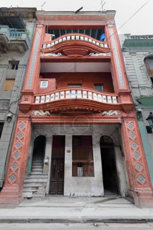 Verwässertes Mietshaus im Zentrum Havannas im eklektischen Stil, rotorange aus den frühen 1900er Jahren mit gewellten Balkonen. La Habana-Kuba-075