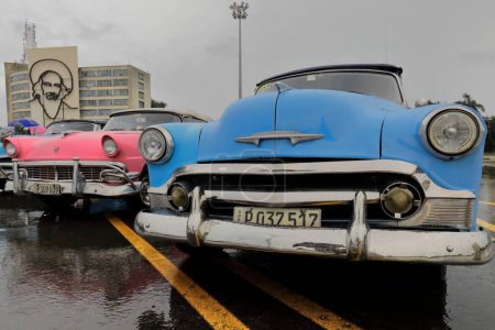 Foto de La Habana, Cuba-7 de octubre de 2019: Coches convertibles clásicos americanos (R - L), Chevrolet Styleline DeLuxe azul 1950-rosa Ford Fairlane Sunliner 1956-azul Chevrolet Bel Air 1953, estacionado en la Plaza de la Revolución. - Imagen libre de derechos
