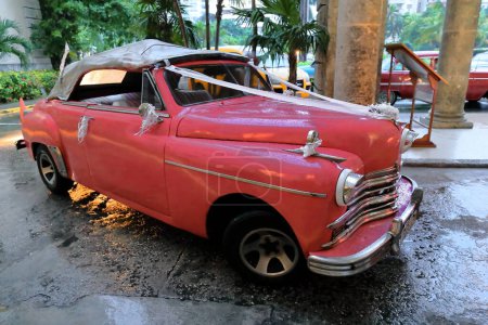 Foto de La Habana, Cuba-07 de octubre de 2019: Pink American classic convertible car -Plymouth Special DeLuxe from 1949- decorated with wedding ornaments, stops at the National Hotel Nacional entrance. La Habana-Cuba. - Imagen libre de derechos