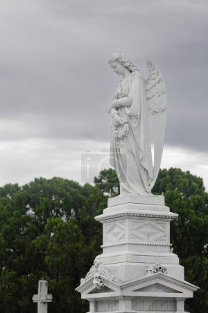 Weibliche Engelsstatue auf einem Sockel, beide aus weißem Marmor, auf dem Friedhof Cementerio de Colon, der für seine vielen kunstvoll geschnitzten Denkmäler bekannt ist, die auf mehr als 500 Mausoleen geschätzt werden. Havanna-Kuba.