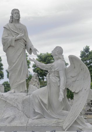 Marmorskulptur eines knienden Engels, der auf Jesus Christus blickt, auf dem Friedhof Cementerio de Colon, der für seine vielen kunstvoll geschnitzten Denkmäler bekannt ist, die auf mehr als 500 Mausoleen geschätzt werden. Havanna-Kuba.