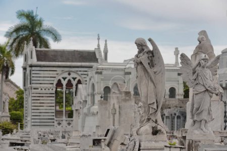 Gruppe weißer Marmorskulpturen auf Sockeln, die die Gräber auf dem Friedhof Cementerio de Colon überragen, der für seine vielen kunstvoll geschnitzten Denkmäler - schätzungsweise 500 plus Mausoleen - bekannt ist. Havanna-Kuba.