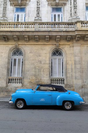 Foto de La Habana, Cuba-8 de octubre de 2019: Vista lateral izquierda de un coche descapotable clásico americano azul Chevrolet Styleline DeLuxe 1952 estacionado junto a la pared de piedra de coral de una casa de estilo ecléctico de principios de 1900 - Imagen libre de derechos