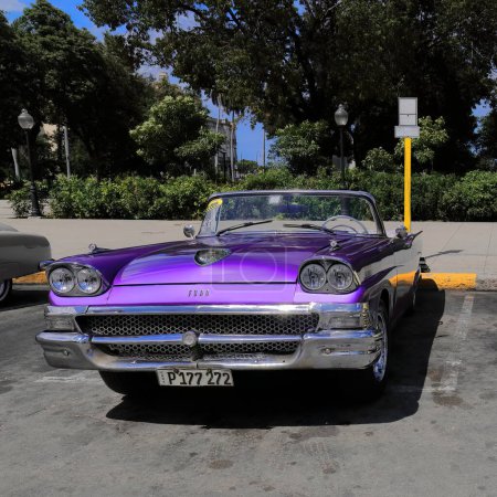 Photo for Havana, Cuba-October 08, 2019: Front view of a purple American classic convertible car -Ford Fairlane 500 Skyliner from 1958- stationed on Plaza 13 de Marzo Square facing the Museum of the Revolution. - Royalty Free Image