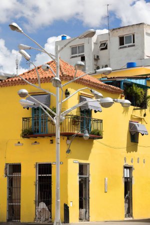 Façade de deux étages, toit pyramidal, murs jaunes, fenêtres barrées, maison coloniale de style baroque datant de 1776 au coin sud-est des rues Chacon et Aguacate, lampadaire à plusieurs têtes. Vieille Havane-Cuba.