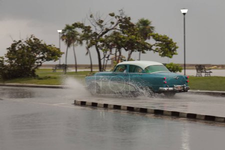 Foto de La Habana, Cuba-8 de octubre de 2019: Coche clásico americano azul-blanco Buick Special 4 Door Tourback Sedan 1953 recorre las calles Jovellar y Marina hasta el Malecon Promenade bajo un fuerte aguacero. - Imagen libre de derechos