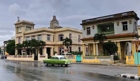 Foto de La Habana, Cuba-8 de octubre de 2019: Green-white American classic car-almendron-Ford Customline 4-door Sedan 1953 conduce por la calle 15 para cruzarse con la calle Linea, mojada después de la fuerte lluvia de la tarde. - Imagen libre de derechos