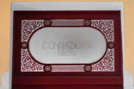 Photo for Cienfuegos, Cuba-October 11, 2019: Maroon-crimsonish painted Contaduria -Accountancy- door with a glazed upper transom window and wood filigree decoration, in the AD 1889 built Tomas Terry Theater. - Royalty Free Image