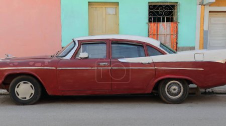 Téléchargez les photos : Trinidad, Cuba-12 octobre 2019 : Vue latérale, rouge-marron et blanc vieille voiture classique américaine almendron, réservoir à manivelle Dodge Royal Berline 4 portes de 1958 stationnée sur une rue de la Plaza Mayor Square - en image libre de droit