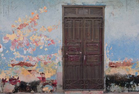 Trinidad, Cuba-October 12, 2019: Dilapidated facade of colonial style house near the Plaza Mayor Square, the chipping displays successive layers of its painting: blue, beige, orange, maroon, green...