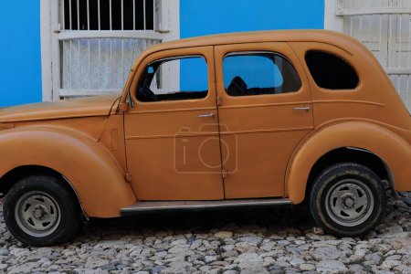 Foto de Trinidad, Cuba-12 de octubre de 2019: Vista lateral, color zanahoria-naranja viejo coche clásico americano-almendro, tanque de yank- Ford Prefecto 4 puertas Salón de 1952 detenido en una calle de la Plaza Mayor. - Imagen libre de derechos
