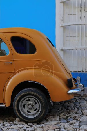 Foto de Trinidad, Cuba-12 de octubre de 2019: Vista lateral, color zanahoria-naranja viejo coche clásico americano-almendro, tanque de yank- Ford Prefecto 4 puertas Salón de 1952 detenido en una calle de la Plaza Mayor. - Imagen libre de derechos