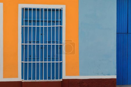 Trinidad, Kuba-12. Oktober 2019: Renovierte Fassade eines Hauses im Kolonialstil in der Nähe des Plaza Mayor mit dem häufigen lokalen Fenster, das lange als Tür dient, Wand in auffälliger Farbkombination bemalt.